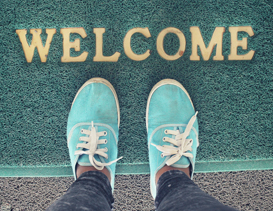 Arial view of feet standing on a doormat that says Welcome